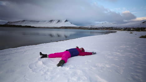 Girl lying down and playing in snowy mountains