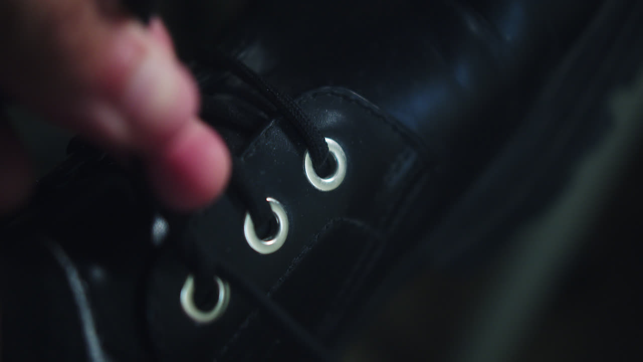 Amazing slow motion shot of a young man tying the laces of his black leather British school shoes and then going for a walk.