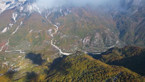 volando a través de las nubes sobre un hermoso valle cubierto de colorido follaje de otoño, en los alpes de albania