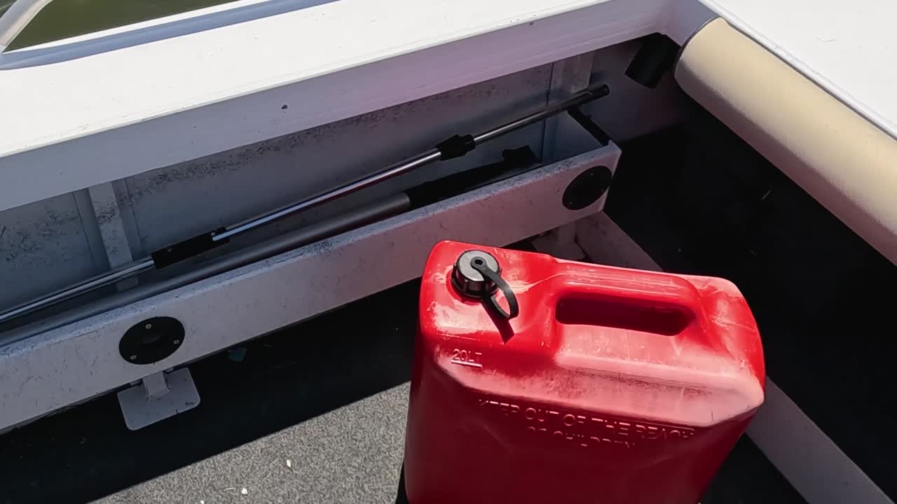 Close-up of a red fuel container placed on a boat deck near seating.