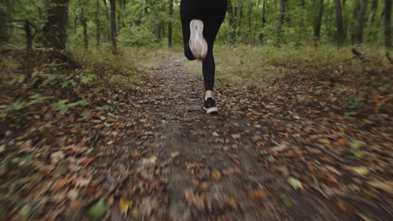 pies de una corredora corriendo por el sendero en el bosque durante el otoño en octubre - cámara lenta