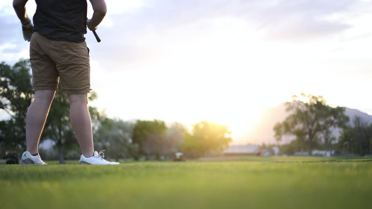 Golfista che swinga e colpisce la palla sul fairway di un campo da golf con bagliore solare