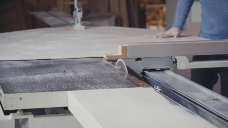 carpintero cortando una hoja de madera contrachapada con una sierra de mesa