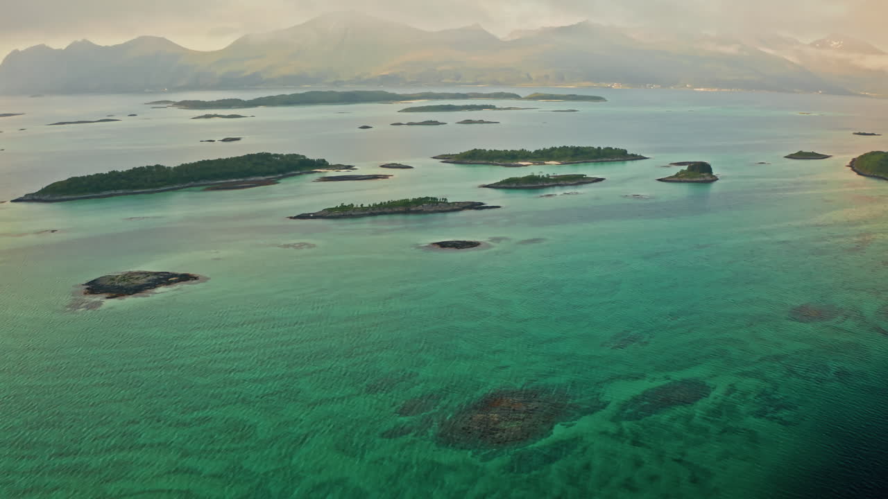 Aerial drone shot over the island of Senja in the Lofoten Ilsands, Norway. High view of the vibrant turquoise sea and the small islands. Breathtaking landscape, untouched natural wonder.