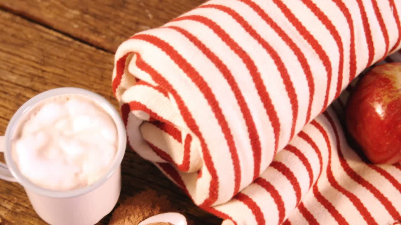 manta enrollada con dos manzanas y una taza de café