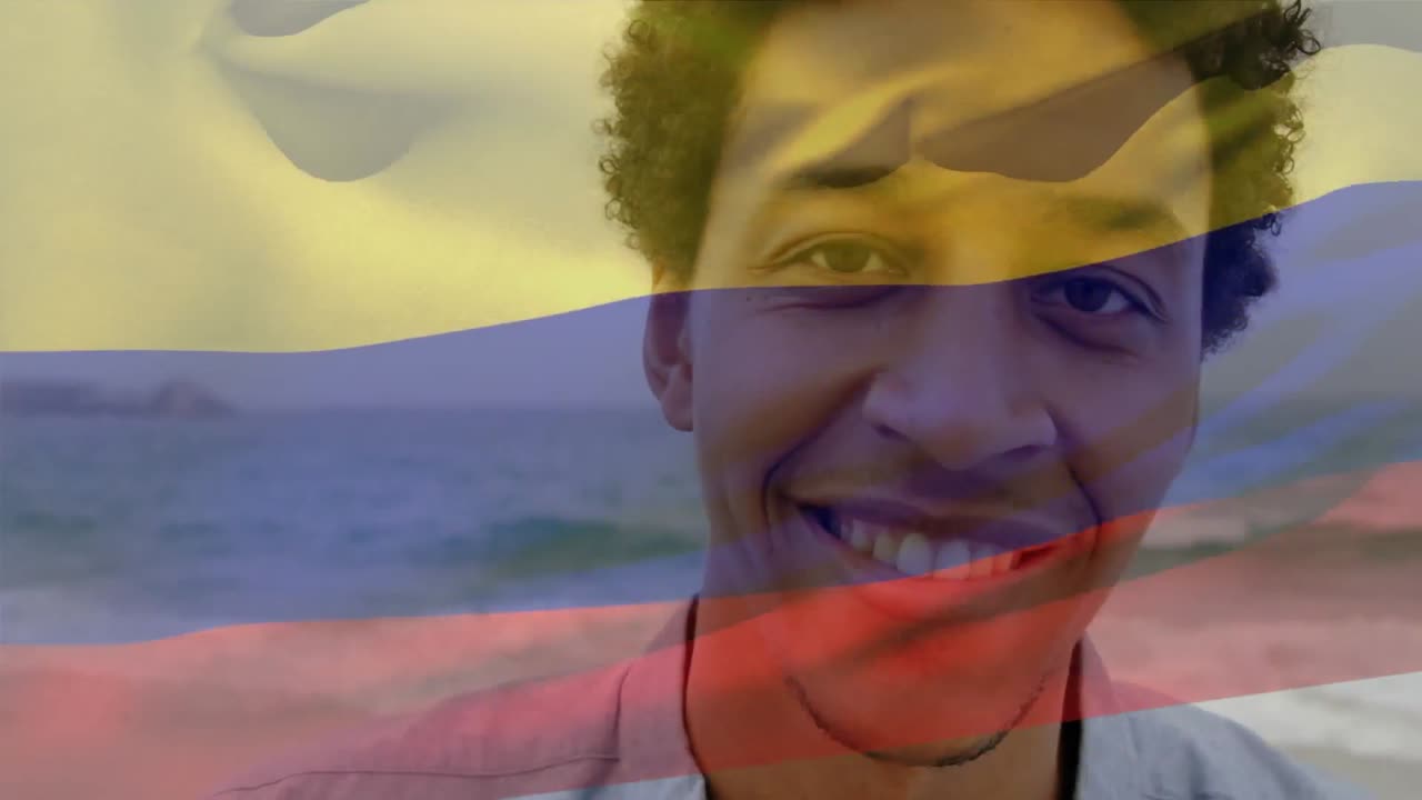 Animação da bandeira da Colômbia a esvoaçar sobre homem afro-americano sorridente em pé com o mar ao fundo