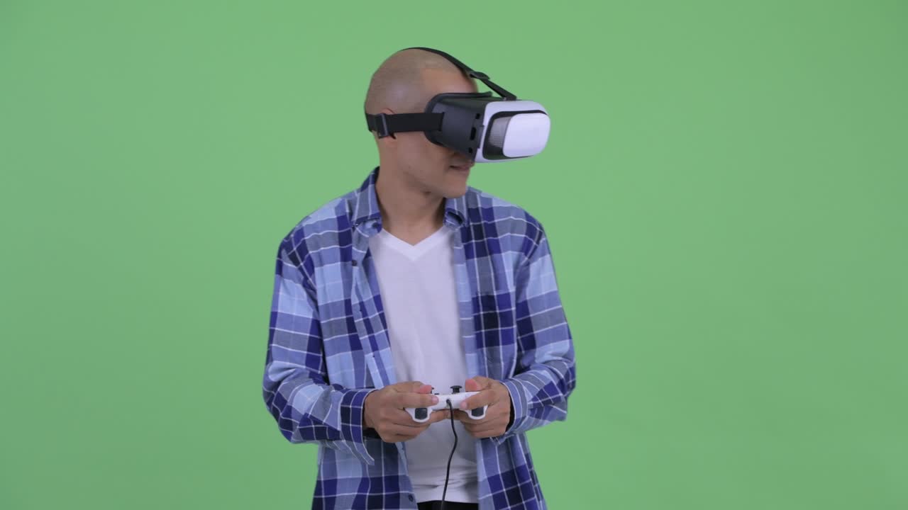 Uomo hipster calvo felice con visore per la realtà virtuale che gioca