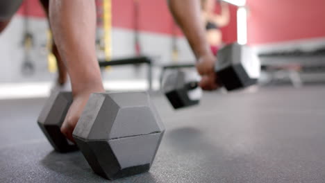 close-up of a person lifting heavy dumbbells at the gym