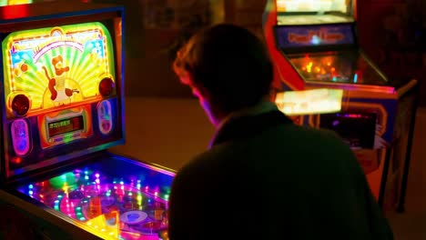 person playing pinball machine in a retro arcade