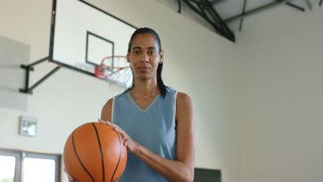 spinning basketball on finger, woman in sports jersey smiling in gymnasium, copy space