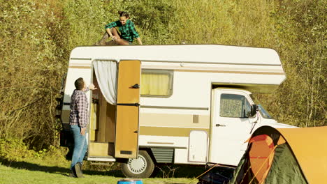 young wife relaxing on top of vintage camper van