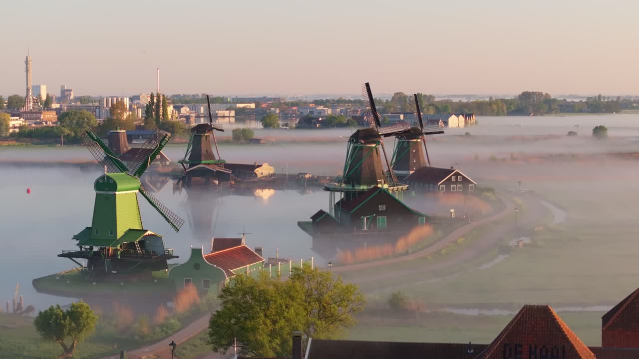 Luftaufnahme von niederländischen Windmühlen und Nebel, der über einem Kanal in Zaanse Schans zieht.