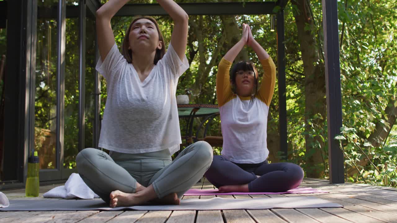 madre y hija asiáticas practicando yoga al aire libre en el jardín