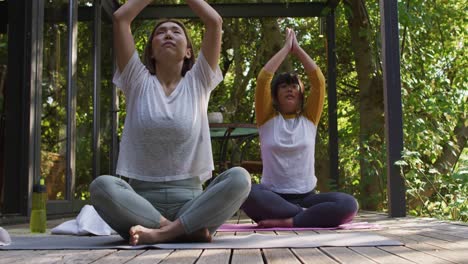 Asian-mother-and-daughter-practicing-yoga-outdoors-in-garden