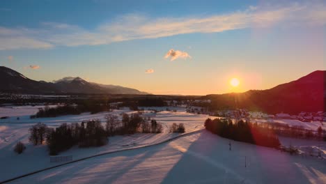 Drohnenaufnahme-Von-Bergen,-Feldern-Und-Landschaft-Im-Winter-Zur-Goldenen-Stunde,-Sonnenaufgang-Mit-Schnee,-Flug-über-Hügel-Und-Felder-Mit-Leuchtenden-Farben