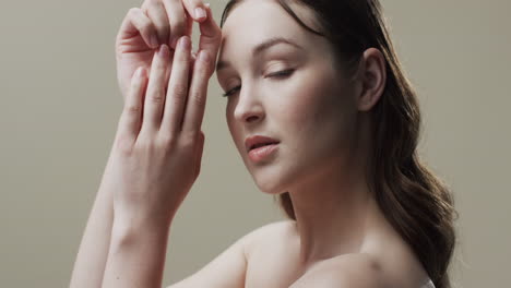 mujer caucásica con cabello castaño y maquillaje tocando su cara, copia espacio, cámara lenta