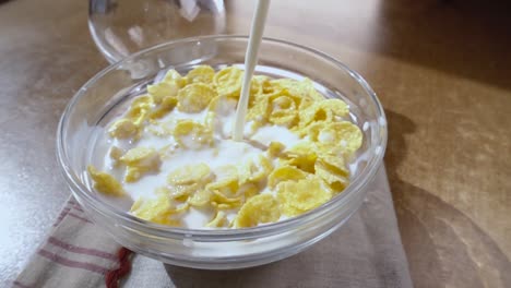 crispy yellow corn flakes into the bowl for the morning a delicious breakfast with milk. slow motion with rotation tracking shot.