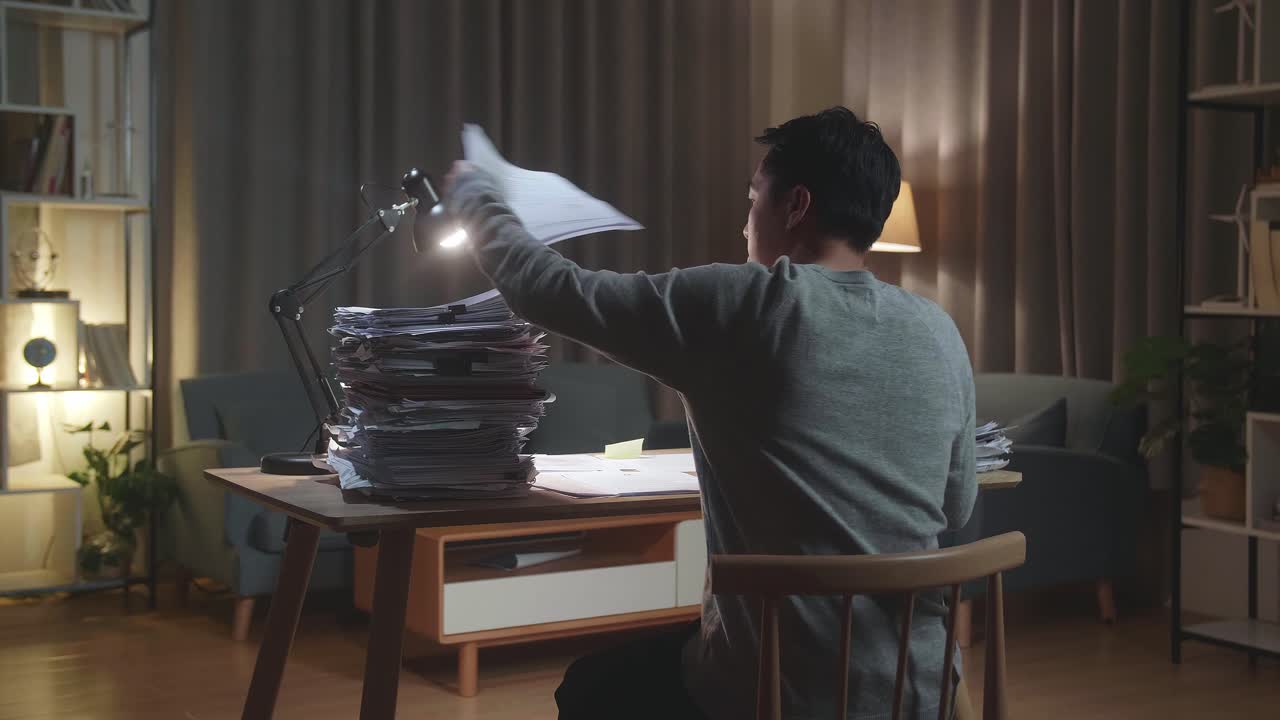 Back View Of Asian Man Working With Documents At The Home