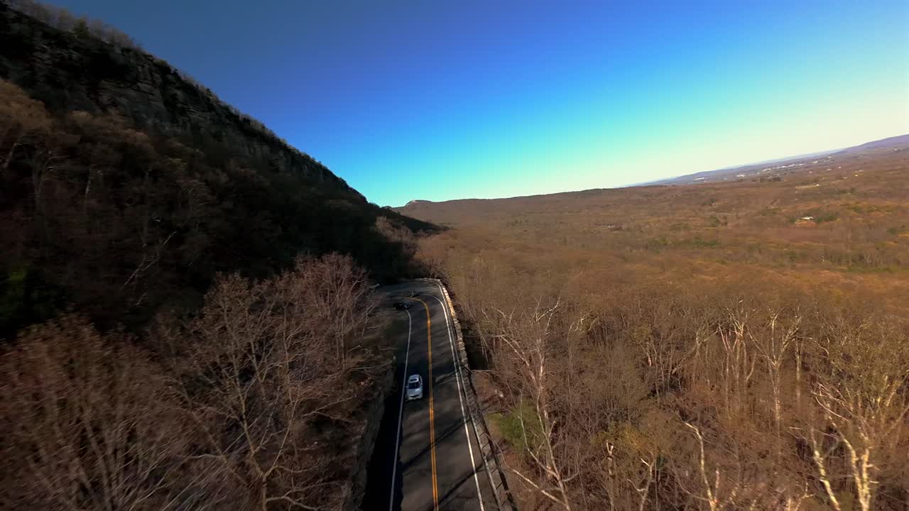 una toma aérea de un avión no tripulado de un camino de campo curvo en las montañas en el norte del estado de nueva york en un día soleado