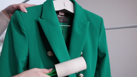using adhesive lint roller on green dry-cleaned suit at laundry shop