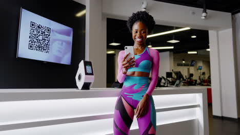 woman smiling while using smartphone to scan qr code for gym check-in
