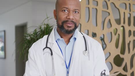 portrait of happy african american male doctor smiling and looking at camera at hospital