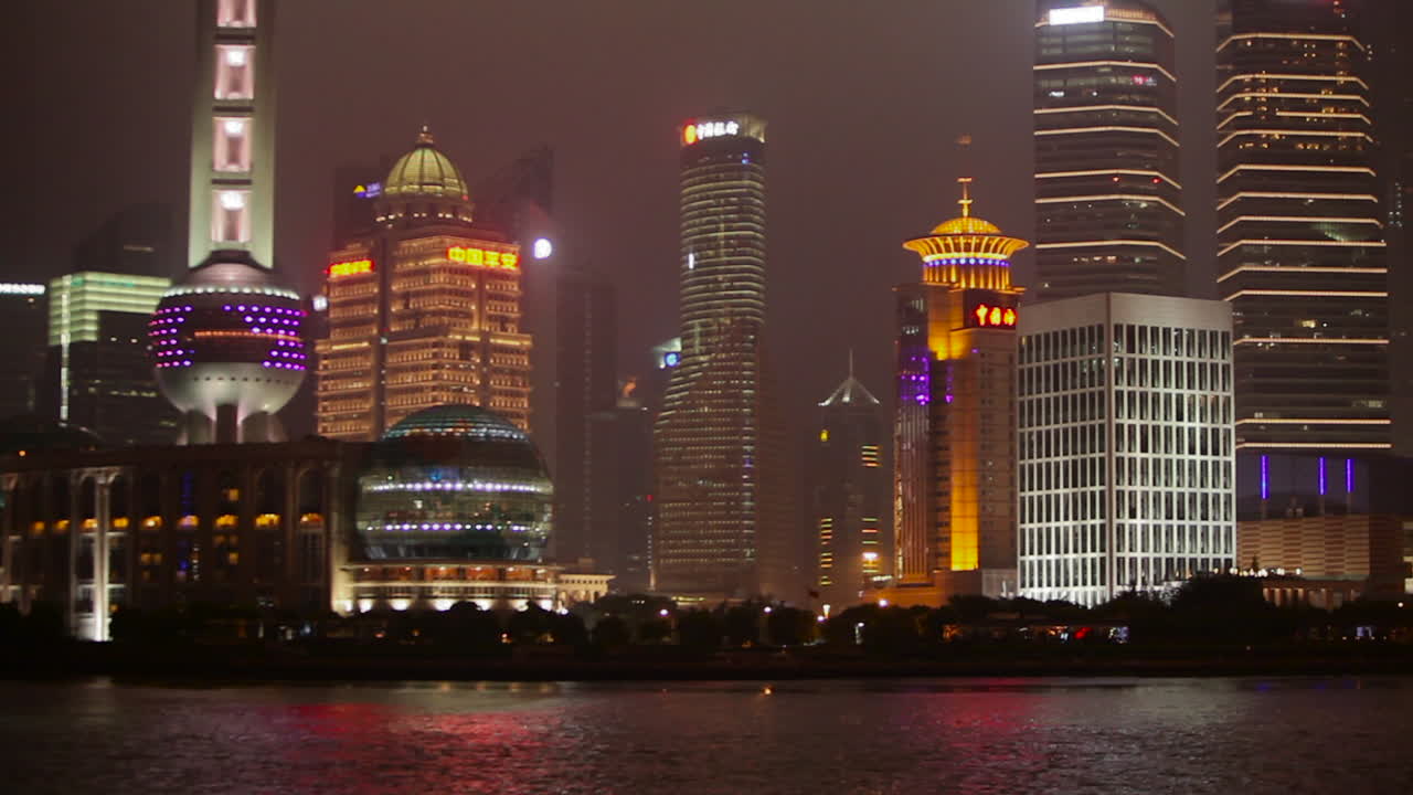el vívido horizonte nocturno de shanghai china con el tráfico fluvial en primer plano y el paso de barcos altos iluminados