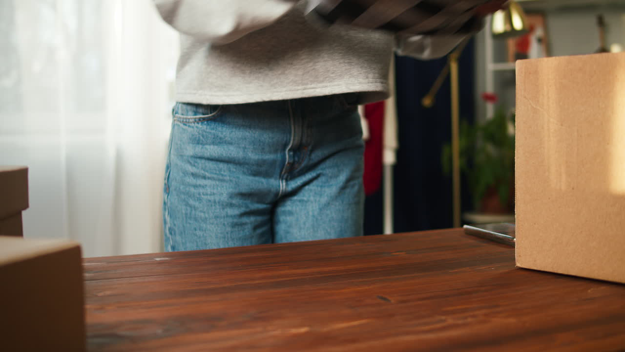 Woman Folding Plaid Clothing and Packing it into a Cardboard Box