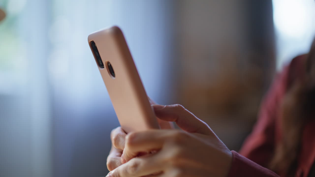 Closeup woman fingers typing cellphone in apartment. Girl texting email message