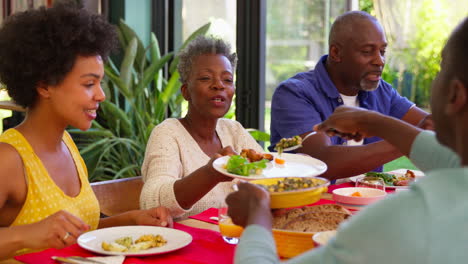 parents with adult offspring sitting around table at home enjoying meal together