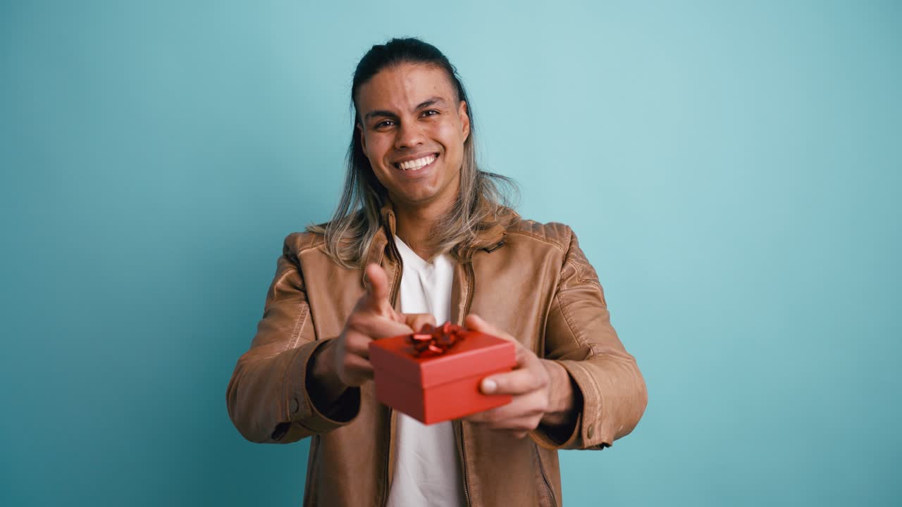 Giovane uomo felice che offre una scatola regalo rossa e sorride