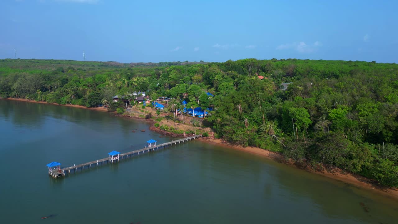 Koh Mak tropical island in Thailand showing luxury glamping tents on the coast near the pier surrounded by lush vegetation. Fantastic aerial view flight drone shot footage from above