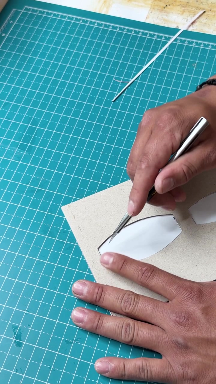 Artisan hands cutting cardboard with precision craft knife on cutting mat