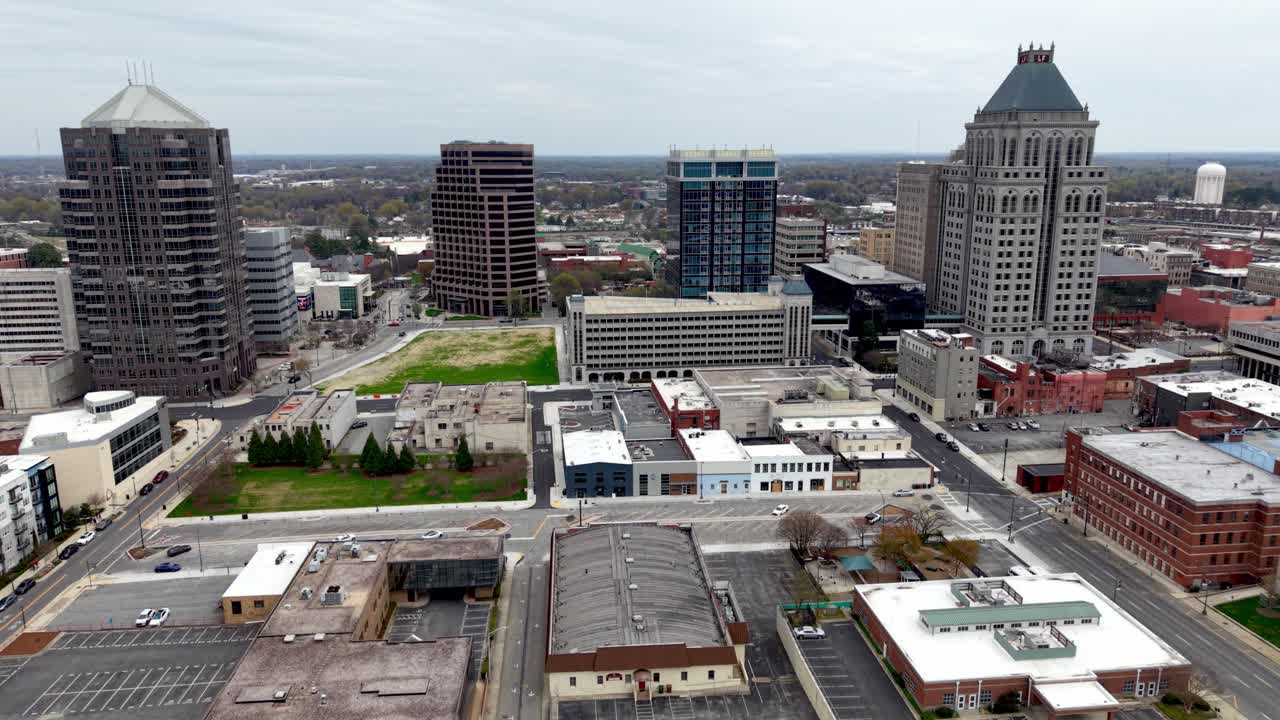 Acercamiento aéreo con dron pasando una grúa de construcción hacia Greensboro, Carolina del Norte