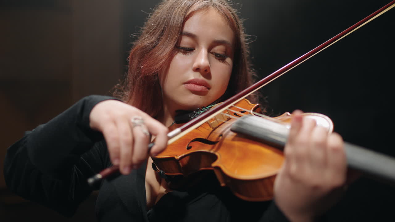 una joven violinista gorda está interpretando música en una escena de una ópera moderna.