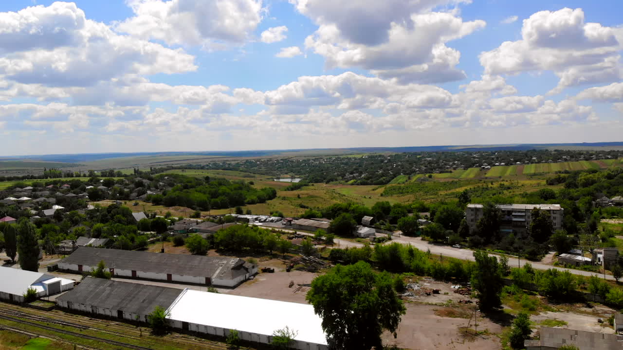 Aerial drone shot of Donduseni city with multiple residential buildings and greenery and fields in Moldova