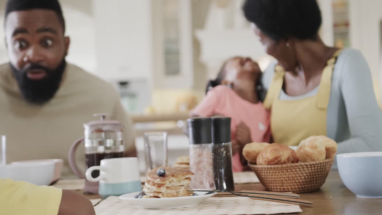 feliz pareja afroamericana con hijo e hija disfrutando de la comida en el comedor, cámara lenta