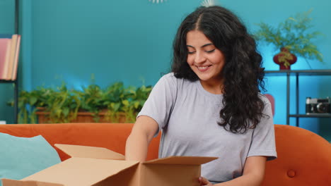 Happy-Arabian-woman-shopper-unpacking-cardboard-box-delivery-parcel-online-shopping-purchase-at-home