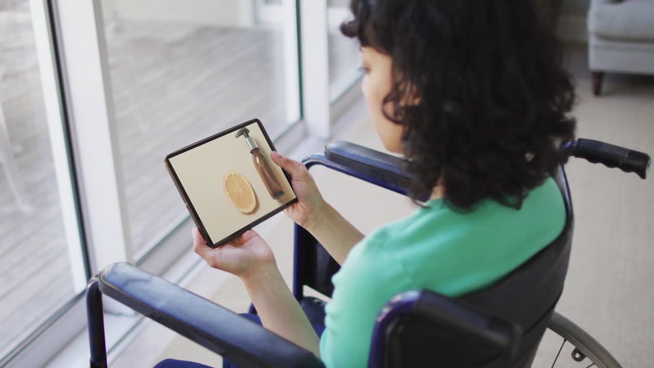 Kvinde af blandet etnicitet i kørestol bruger tablet, shopper skønhedsprodukter online, i slow motion.