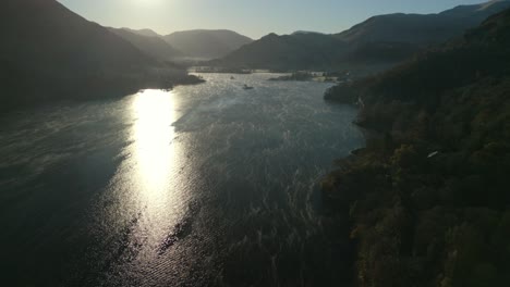 Lago-Tranquilo-Con-Niebla-Superficial-En-Movimiento-Con-Amanecer-Reflejado-En-El-Agua-Y-Siluetas-De-Montaña-En-Otoño