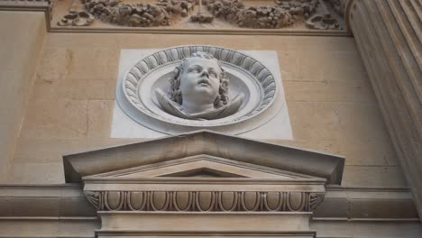 vertical pan from a golden leaf ornament to an angel's head's statue