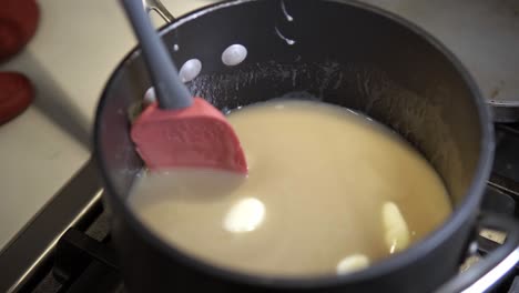 A-young-girl-stirs-a-caramel-mix-heating-up-on-the-stove-while-baking-millionaire-shortbread-cookies