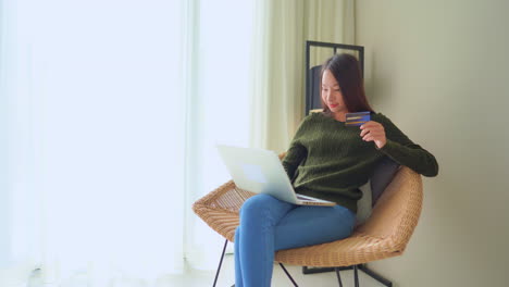 a young asian woman buying something online with her credit card