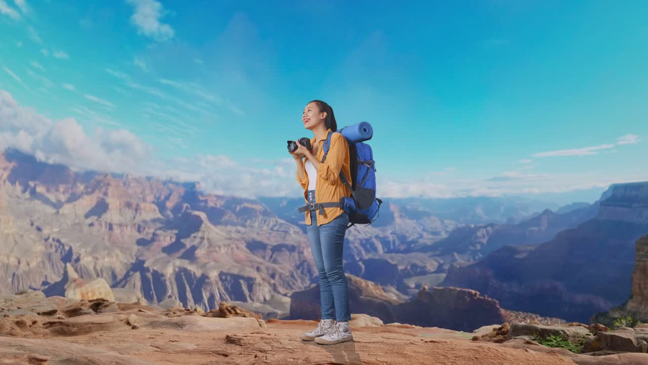 Full Body Side View Of Asian Female Hiker With Mountaineering Backpack Smiling And Holding A Camera In Her Hands Then Looking Around While Traveling At The Top Of Mountain