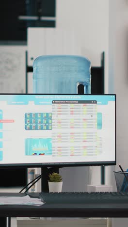 Vertical video Company workspace with nobody in and business figures on computer monitors