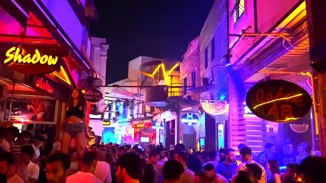 Two hot girls dancing on tables at a popular famous party street in Bodrum Turkey, fun summer nights on vacation, 4K shot