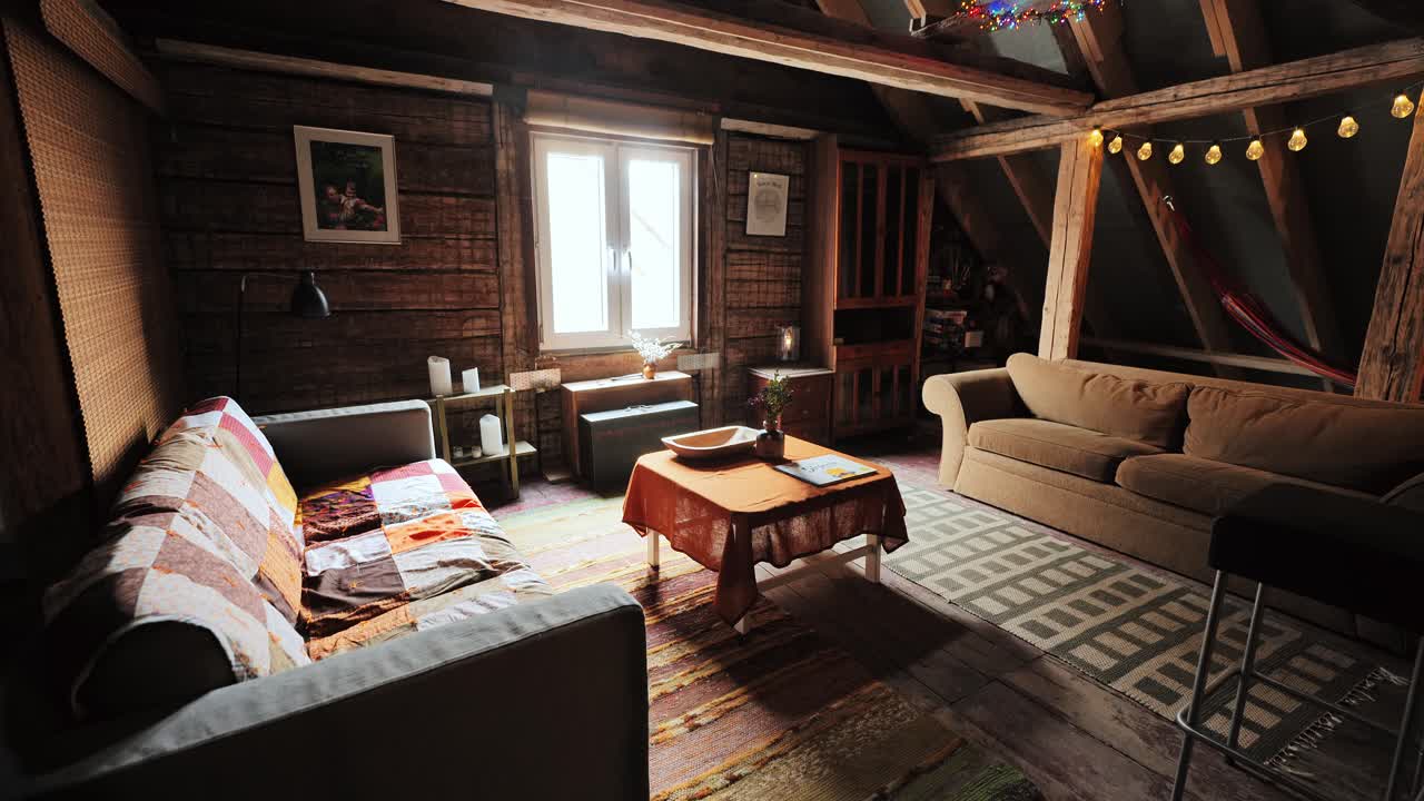 Sunlight fills cozy wooden attic with vintage decor, couches, and handmade rugs