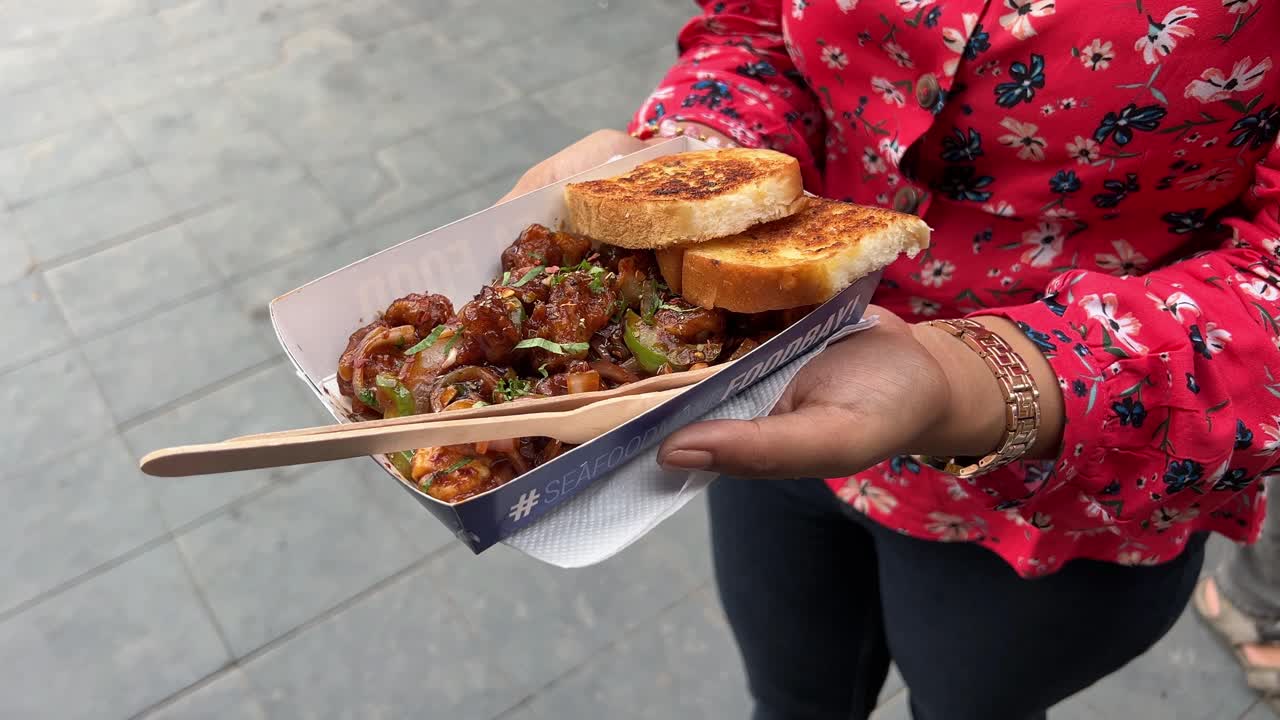 A girl holding bread and spicy fried squid in market