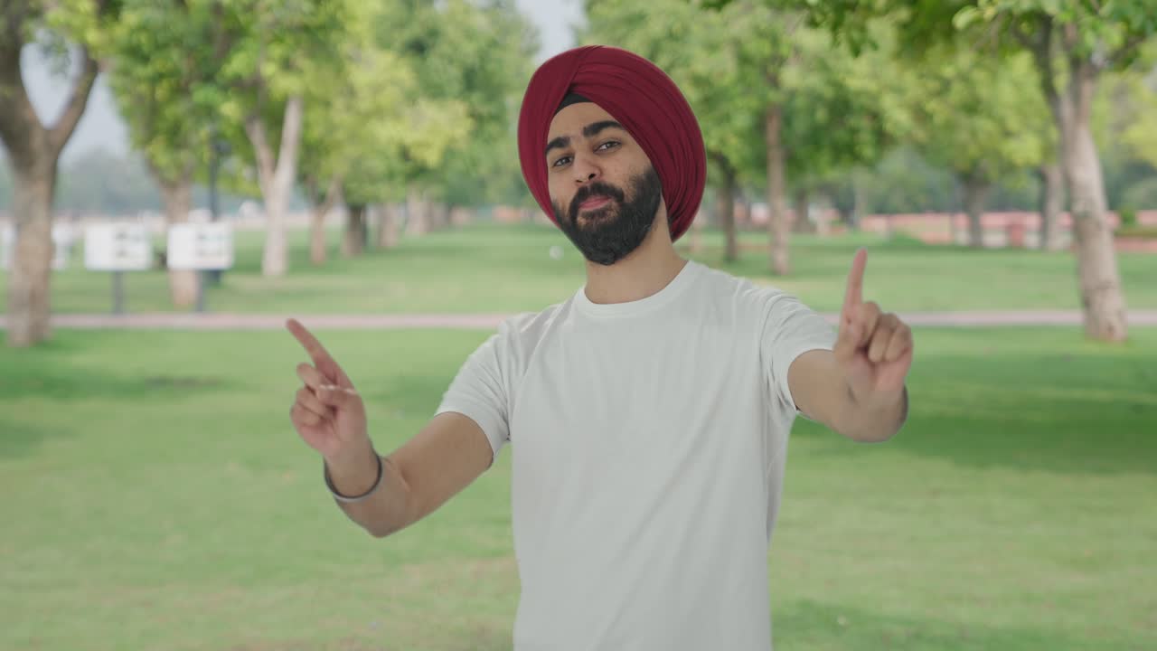 Uomo indiano Sikh felice che balla e fa Bhangra nel parco