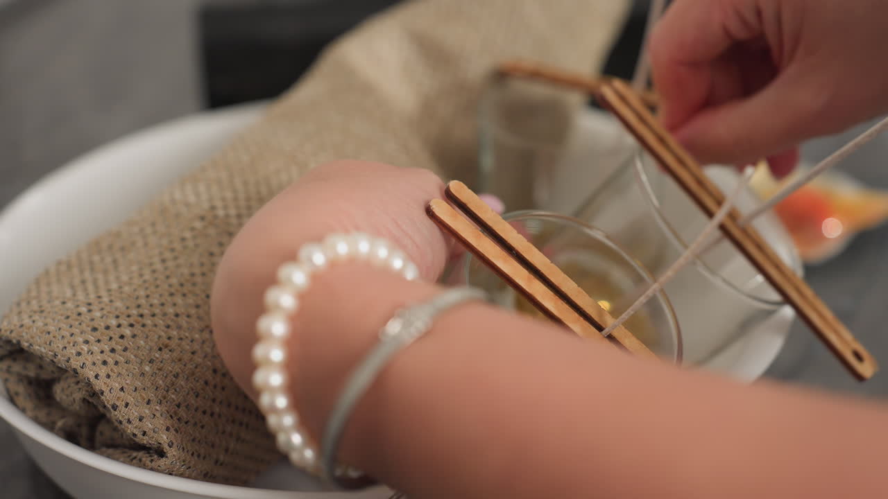 Close-up hand view of lady arranging glass cups inside white bowl using sack bag for securing, preparing candle holders with wicks inside cups for crafting or decorative purposes